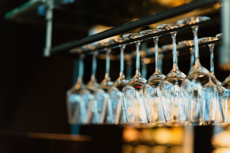 Clean wine glasses hanging above a bar