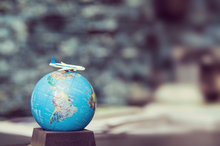 Model airplane circling a globe for wine travel guides